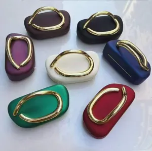 Multi-color acrylic mini evening bags featuring distinct large gold curved metal handles.