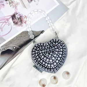 Detailaufnahme einer glitzernden Strass-Herz-Tasche mit klarem Perlenhenkel und Verschluss.