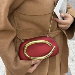 Detail view of the retro mini evening crossbody bag featuring a striking gold C-shaped metal handle.