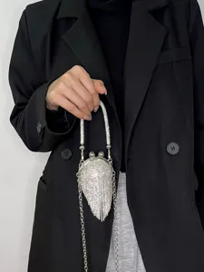 Detailansicht einer glitzernden Strass-Fransen-Minibag mit Kussverschluss in der Hand, glänzend.