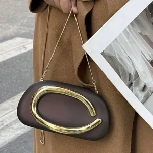 Detail shot of the unique sculptural gold loop handle and smooth brown acrylic evening clutch.