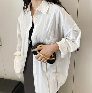Detail view of mini black evening bag with gold ring handle and chain strap for women.