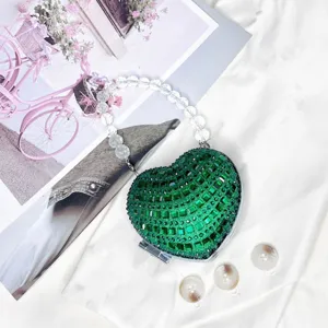 Nahaufnahme einer glitzernden grünen Strass-Herz-Tasche mit Kristallperlenhenkel.