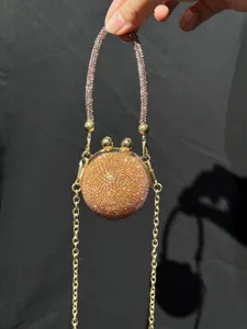 Nahaufnahme einer glitzernden Strass-Rundminitasche mit Kristallgriff und Goldkette.