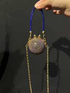 Nahaufnahme einer Mini Kristall runden Clutch mit blauen Strasssteinen und Goldkette.