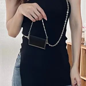 Gros plan détaillé du mini porte-carte en cuir noir avec chaîne argentée et belles coutures.