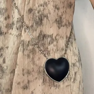 Nahaufnahme Detailansicht einer schwarzen herzförmigen Mini Umhängetasche mit Kette.