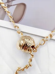 Gold metal chain waist belt with white leather weaving and quilted ball pendant detail.