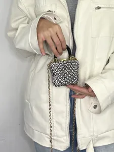 Exquisites Detail einer Mini-Strass-Box-Tasche mit funkelnden Kristallen und goldener Kette.