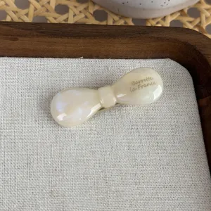 Nahaufnahme der cremefarbenen Acetat Schleifen-Haarspange mit feiner Textur und Aufdruck.