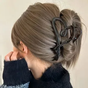 Dettaglio di elegante molletta per capelli a cuore nera, ideale per acconciature chic.