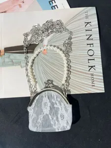 Vintage lace kiss lock coin purse with pearl handle and silver chain strap detail view.