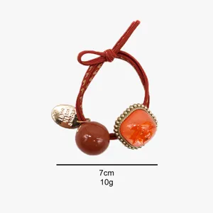 Vue détaillée d'un chouchou coréen avec bande élastique rouge et perle en résine élégante.