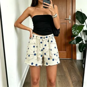 Detailed view of women's denim shorts with blue polka dots, grommets, and cute drawstrings.