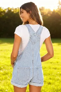 Detailed view of light blue denim bib shorts worn outdoors, featuring classic pockets and straps.