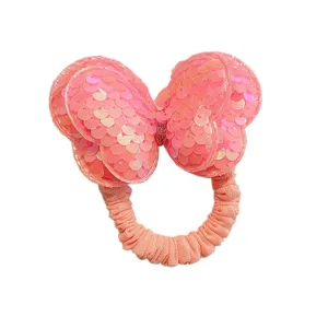 Primo piano dettagliato di un elastico per capelli con fiocco in paillettes rosa brillante.