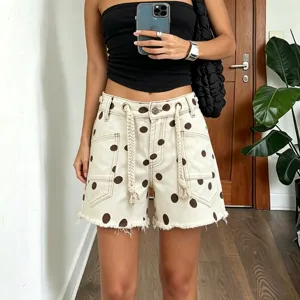Detailed view of women's polka dot denim shorts featuring braided drawstrings and raw hem.