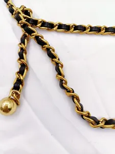 Gold metal and black leather woven chain detail close-up fashion accessory piece