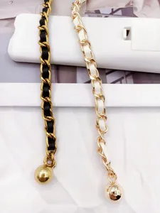 Stylish women's metal chain belt with leather weave and ball pendant, trendy accessory.