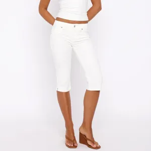 Detailed view of women white cropped jeans featuring stretch fabric and ankle slit design.