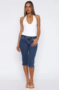 Close-up detail shot of womens stretch denim capri pants featuring slim fit and split hem.