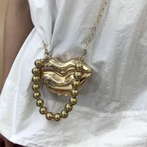 Metallische Mini Lippen Umhängetasche Detail, glänzendes Gold und dicker Perlenhenkel.