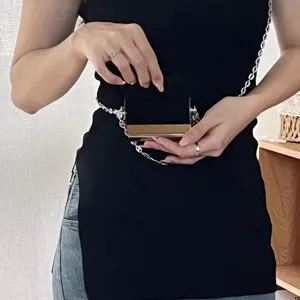 Vue détaillée du mini sac porte-cartes bandoulière en métal pour femme porté à la taille.