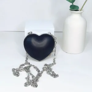 Schwarze PU Leder Umhängetasche in Herzform mit silberner Kette für elegante Abende.