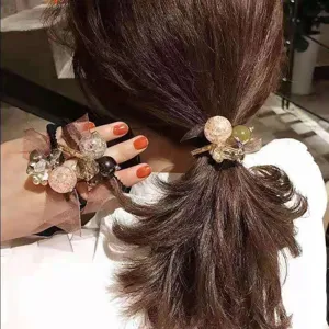 Primo piano di un elastico per capelli con perle di cristallo su coda di cavallo e polso.