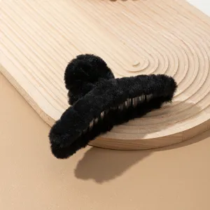 Primer plano detallado de la pinza de pelo de peluche negro, mostrando su textura suave y agarre.