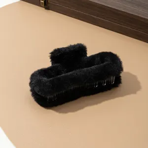 Primer plano detallado de la pinza de pelo de peluche negro con textura suave y elegante.