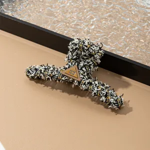 Pinza para cabello de tweed negro y blanco con placa metálica triangular para peinados chic.