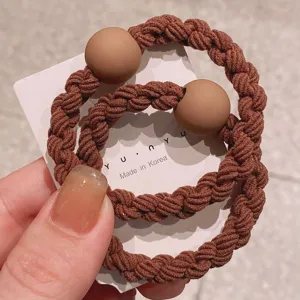 Detailed close-up of brown braided hair tie with matte bead, stylish ponytail holder.