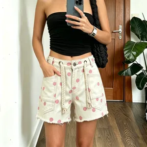 Detailed shot of women denim shorts with pink polka dots, thick braided drawstrings and metal eyelets.