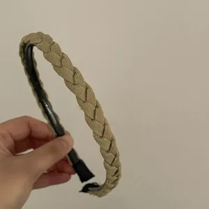 Close-up detail of the braided khaki headband, showing textured fabric and slim frame.