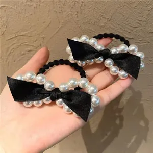 Close-up detail of a charming black pearl hair scrunchie featuring an elegant fabric bow.