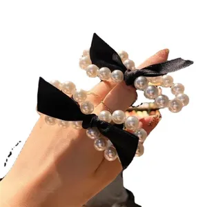 Detail view of pearl hair tie featuring elegant black bow, perfect for daily styling.
