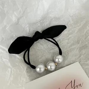 Vue détaillée de l'élastique à cheveux nœud noir avec perles et perles dorées.