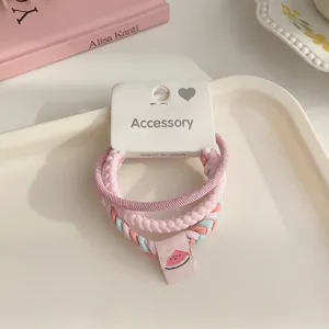 Detail shot of a 3-piece braided hair tie set in pink tones with a cute watermelon charm.