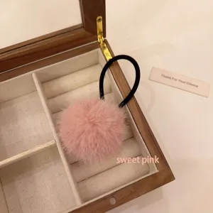 Pink plush pom pom hair tie, fluffy ball hair accessory for women ponytail detail shot.