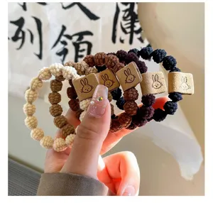 Close-up of cute knitted hair ties with rabbit leather patch, elastic rubber bands in multi colors.