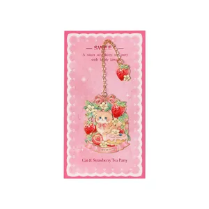 Delizioso segnalibro in metallo con design di gatto e fragola su carta rosa decorata.