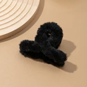 Vista detallada de la pinza de pelo de peluche negro, textura suave y agarre firme y seguro.