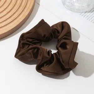 Brown satin scrunchie detail view, elegant hair tie for women, soft fabric texture close up.