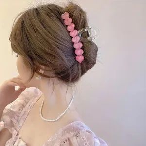 Vista dettagliata di una grande molletta per capelli rosa a cuore, elegante accessorio donna.