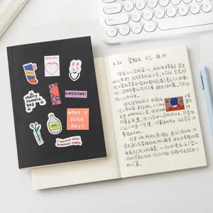 Quaderno nero con copertina rigida, adesivi decorativi carini e pagine a righe per appunti.