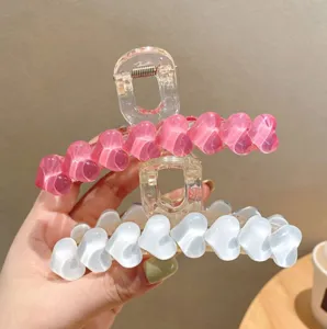 Vista dettagliata di grandi mollette per capelli a cuore in resina rosa e bianca design.