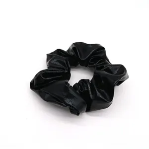 Close-up detail of black shiny hair scrunchie, elegant hair tie accessory for daily wear.
