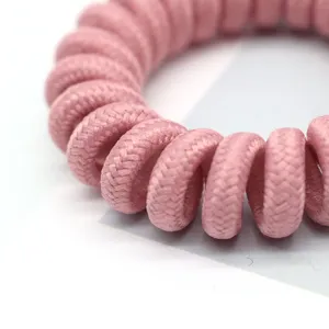 Close-up detail of a pink fabric-wrapped coiled hair tie, showing soft textured surface.