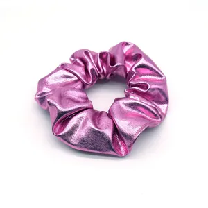 Close-up detail shot of the shiny metallic pink hair scrunchie, showing fine texture.